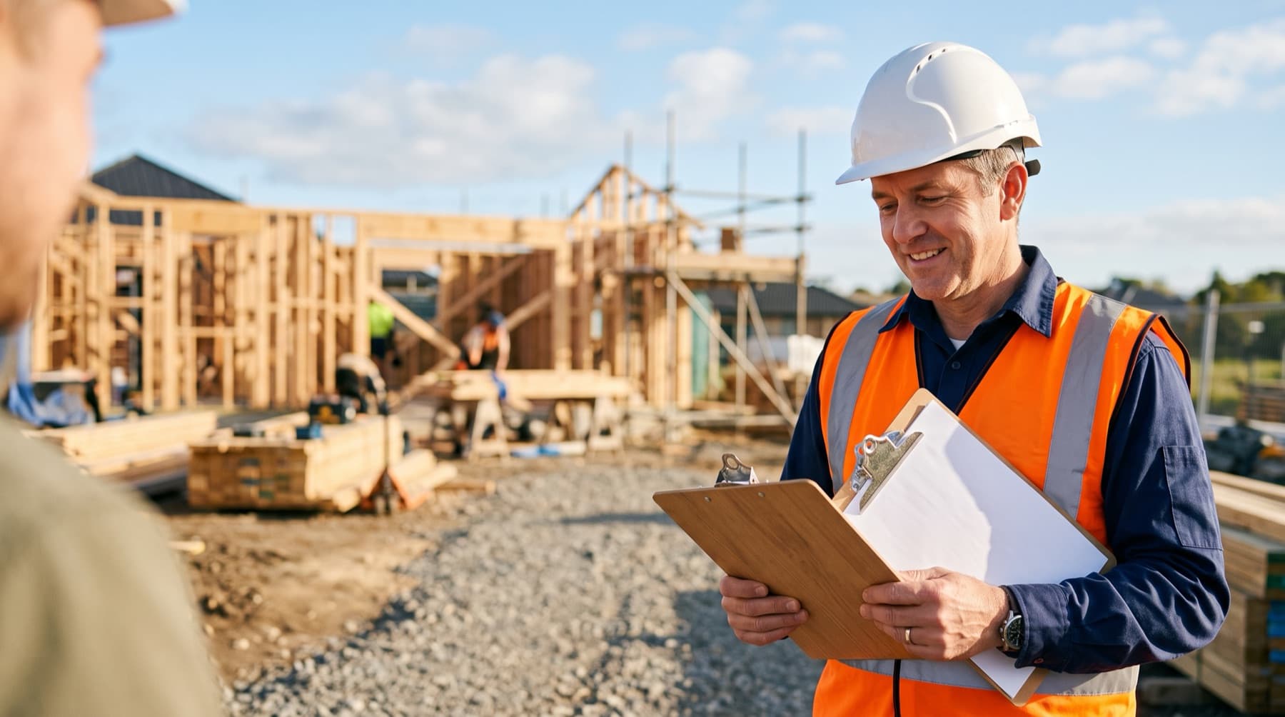 Site supervisor in a hi-vis vest reading a method statement on a house-building site